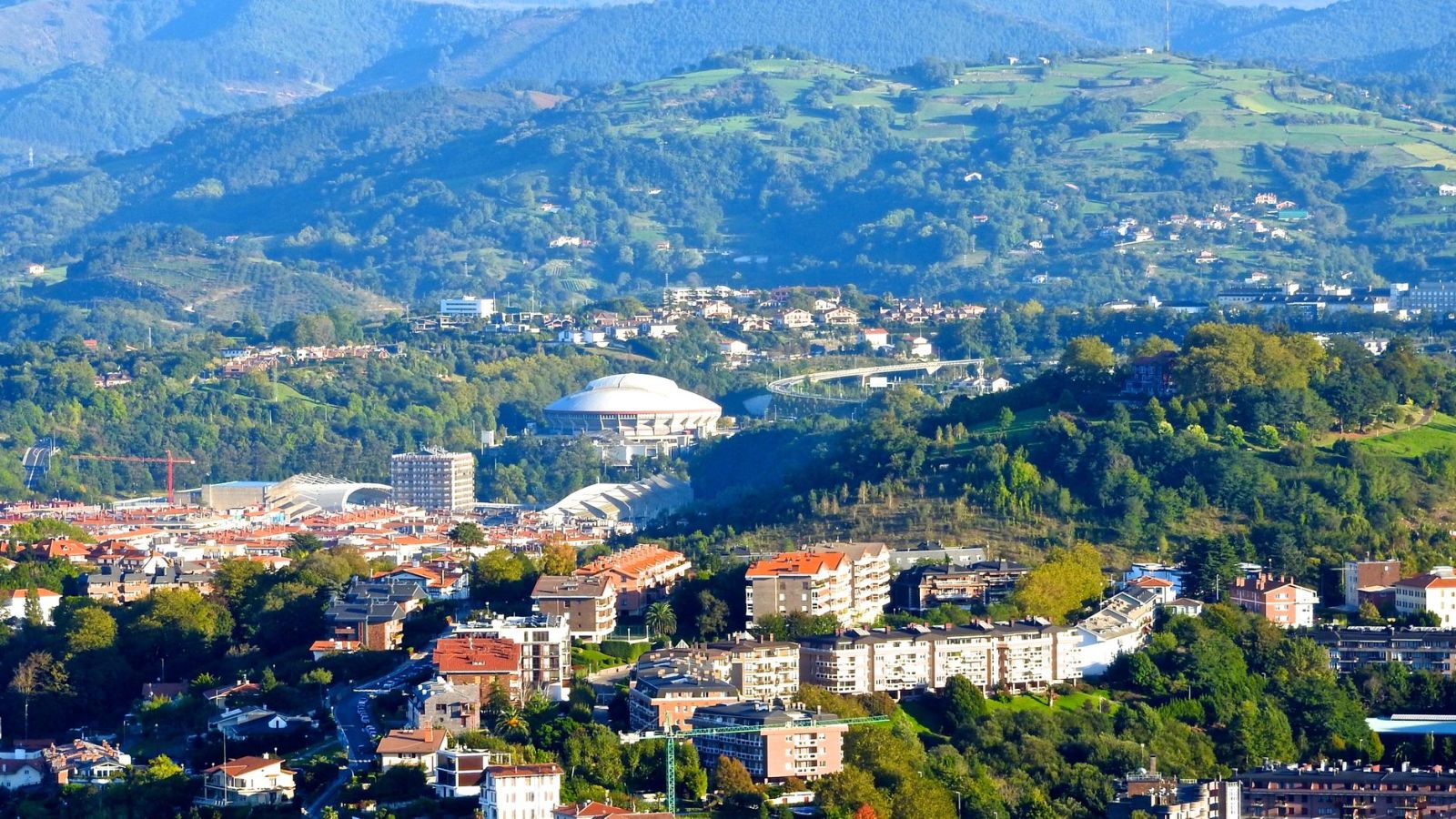 Aerial view of Donostia-San Sebastián with scenic hills and city buildings.